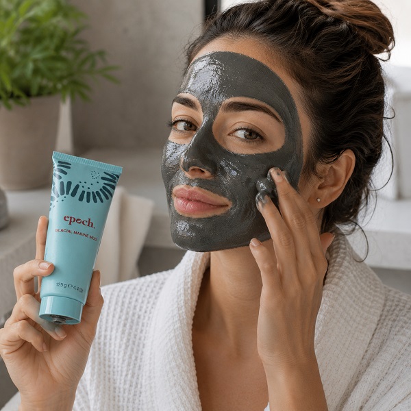 Frau trägt Nu Skin Epoch Glacial Marine Mud Schlammmaske auf Gesicht auf